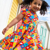 Child wearing Frugi's favourite things Spring skater dress with beach huts in the background