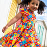 Child wearing Frugi's favourite things Spring skater dress with beach huts in the background