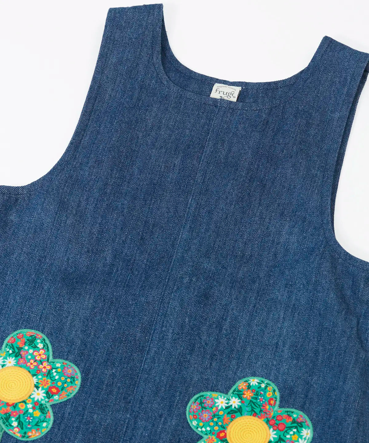 Frugi organic cotton mid wash denim kids pinafore dress laid flat showing a close up of a the shoulder straps and scoop neck line 