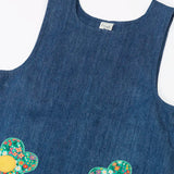Frugi organic cotton mid wash denim kids pinafore dress laid flat showing a close up of a the shoulder straps and scoop neck line 