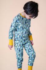 A child wearing the Frugi sundown pyjamas in penguin waddle available at Babipur. A pyjama set in light blue with a penguin design all over and yellow trim