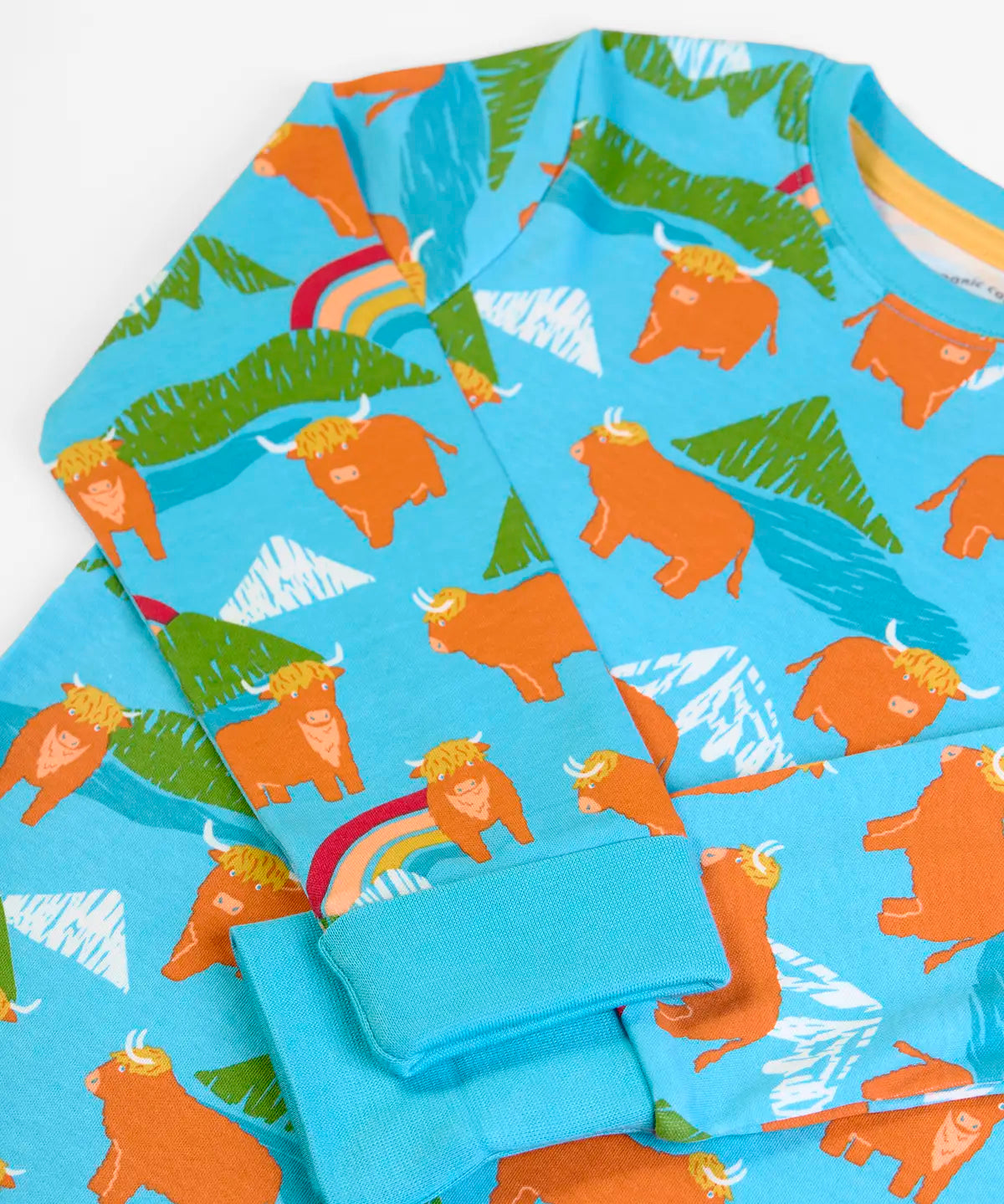 Frugi GOTS 100% organic cotton kids pyjama light blue top with a repeating highland cow and mountain print and turn up cuffs