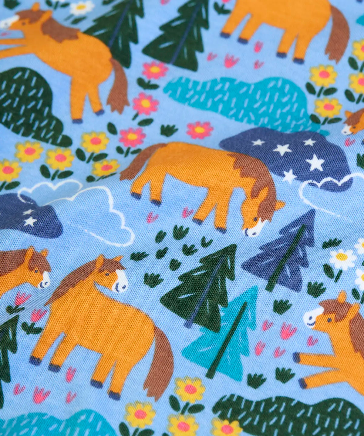 Frugi  kids pyjamas showing a close up of the repeating Shetland pony and horse print on light blue organic cotton fabric
