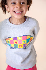 A close up of a child wearing the Frugi Superb Stitched Skateboard sweatshirt available at Babipur showing the embroidered skateboard design detail