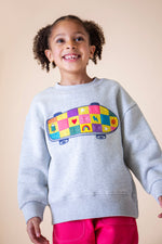 A child wearing the Frugi Superb Stitched Skateboard sweatshirt available at Babipur. A GOTS organic cotton sweater i with a embroidered skateboard with checkerboard design.