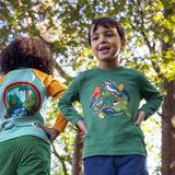 A child standing outside by trees and wearing the Frugi kids terrific applique top in holly green/birds available at Babipur.