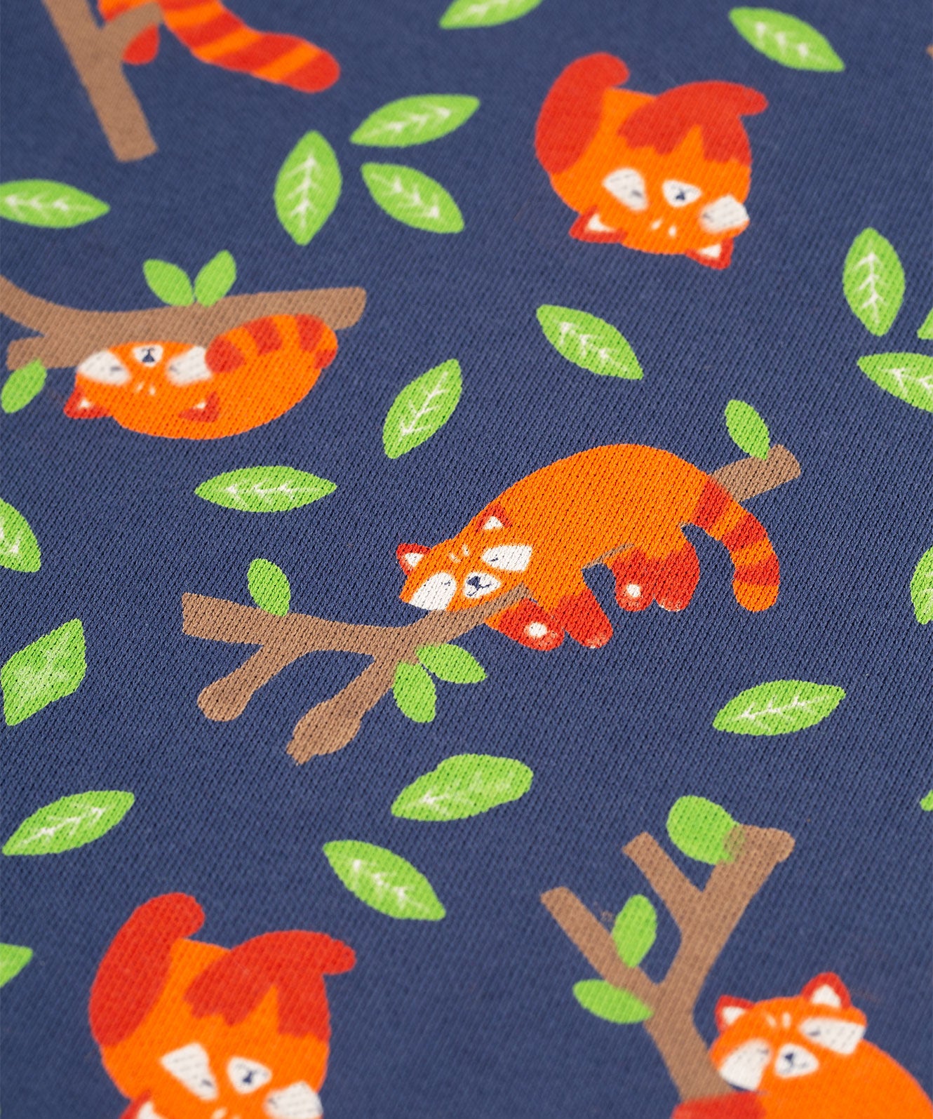 A closer look at the Red Panda Pals print. The image shows a navy blue fabric, with cute sleeping red pandas on their own or sleeping on a tree branch, a long with green leaves