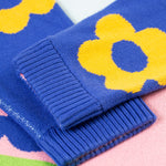 A closer look at the ribbed, knitted cuffs on the Frugi Zola Reversible Knitted Dress - Blue Tang/Retro Floral. The image shows royal blue sleeves with bold, yellow floral prints