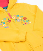 A close up of the Frugi kids carbis hoodie in bumblebee/flowers showing the delicate flower embroidery and pouch pocket detail on yellow organic cotton fabric.
