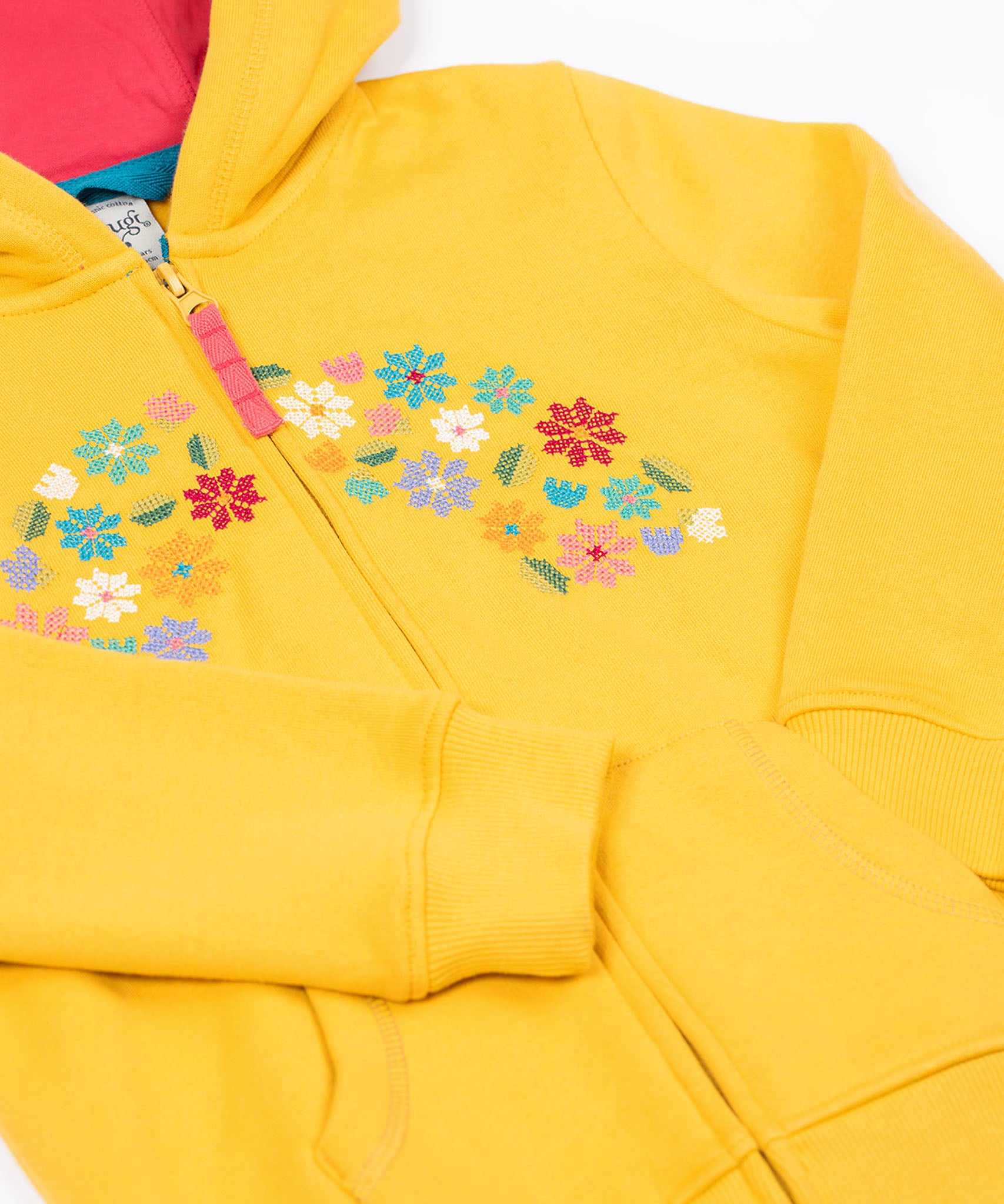 A close up of the Frugi kids carbis hoodie in bumblebee/flowers showing the delicate flower embroidery and pouch pocket detail on yellow organic cotton fabric.