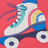 A close up of the white and blue roller blade appliqué against light pink fabric