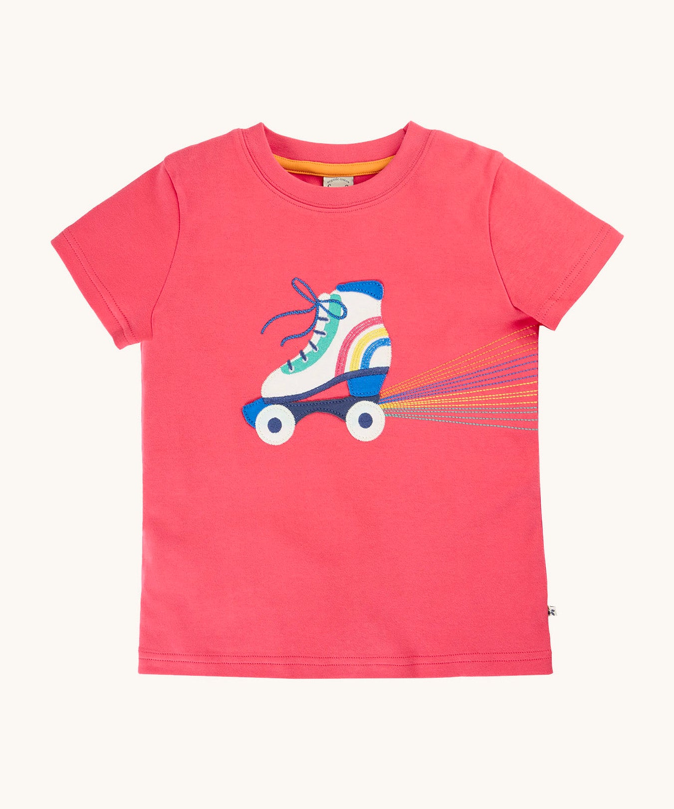 Frugi organic cotton short sleeve t-shirt laid flat. In light pink with a white and blue roller skate appliqué on the front
