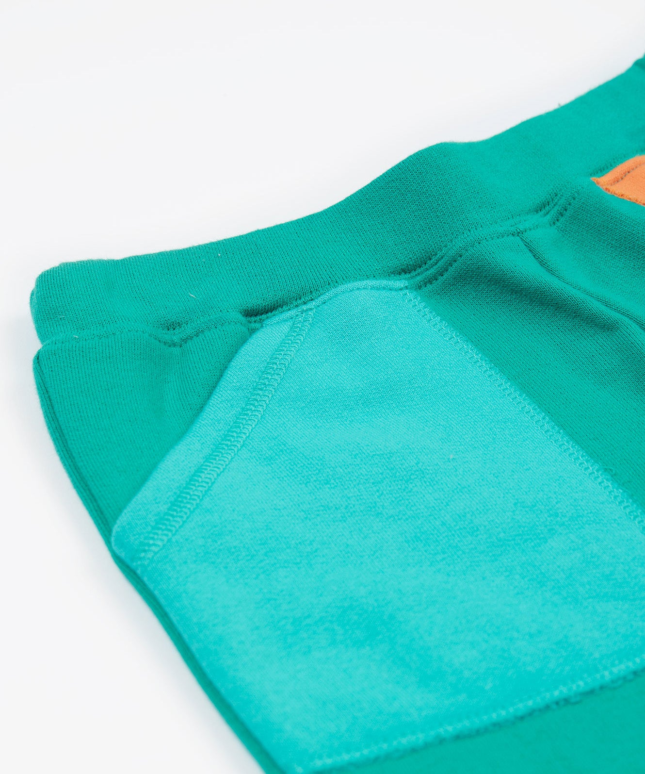 Frugi green joggers with a blue, orange yellow and green colour block design waist detail