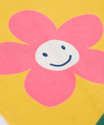 A close up of the  Frugi kids luana bumblebee/flower leggings showing the pink flower print detail on yellow organic cotton fabric.