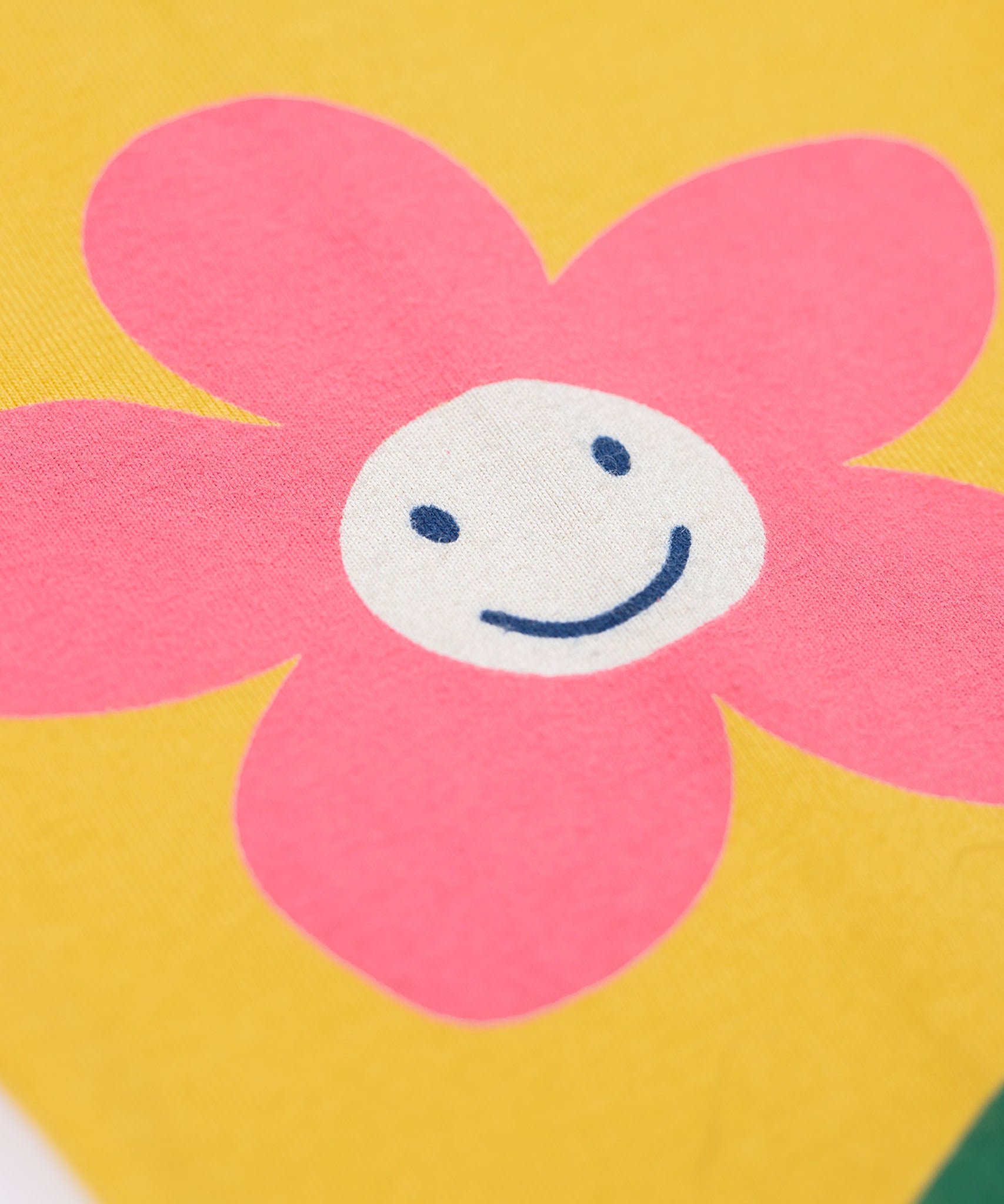 A close up of the  Frugi kids luana bumblebee/flower leggings showing the pink flower print detail on yellow organic cotton fabric.