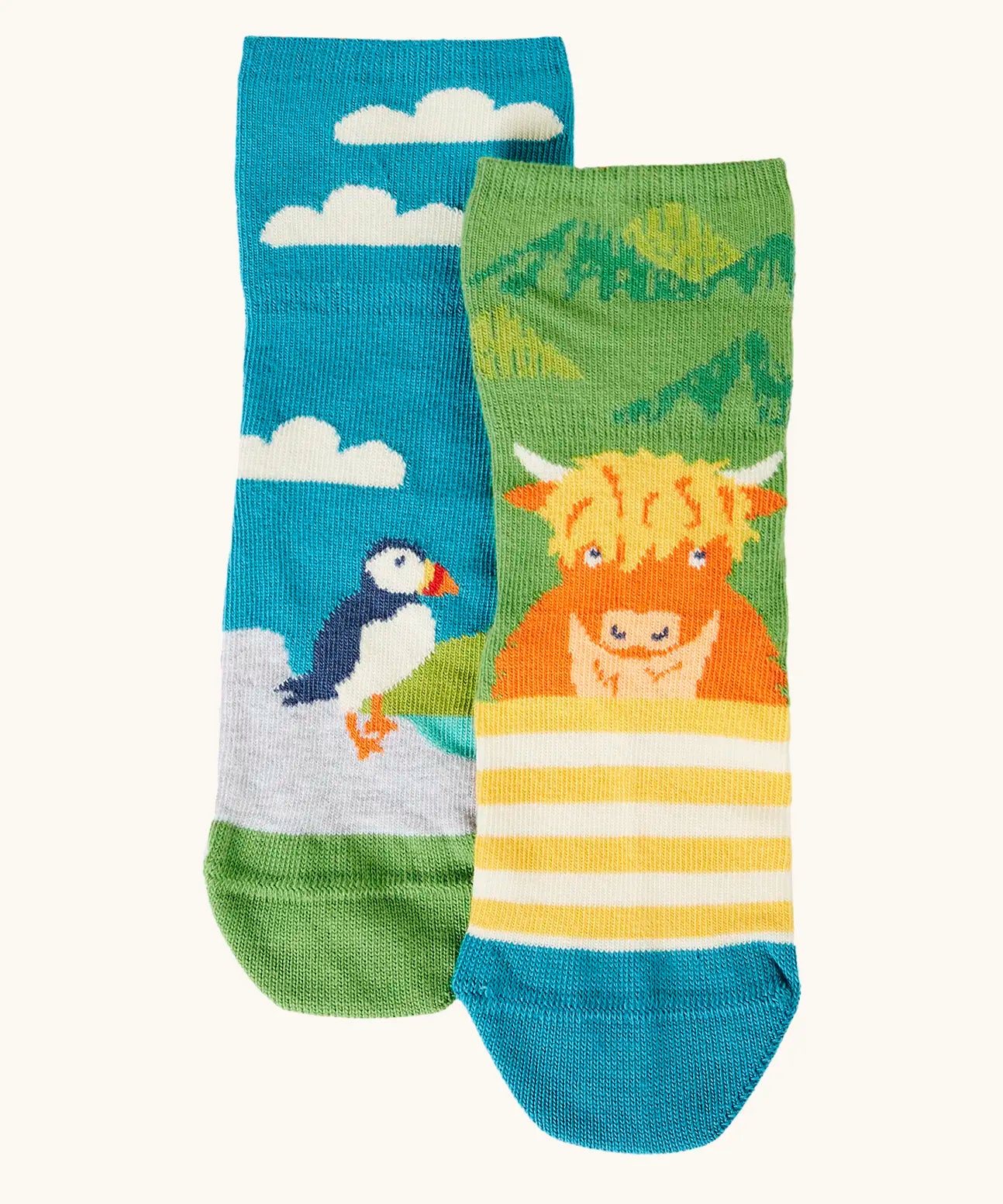 Frugi GOTS organic cotton socks 2 pack  One pair with yellow stripes with a little Highland cow other has a blue sky landscape with a puffin with details hidden under the cuff