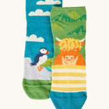 Frugi GOTS organic cotton socks 2 pack  One pair with yellow stripes with a little Highland cow other has a blue sky landscape with a puffin with details hidden under the cuff