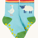 Frugi organic sock laid flat. In light blue with a white goose on one sock and a white sheep on the other.