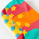 A close up of the underside of the Frugi organic cotton 2 pack socks laid flat. In bright striped colours with little star grip panels