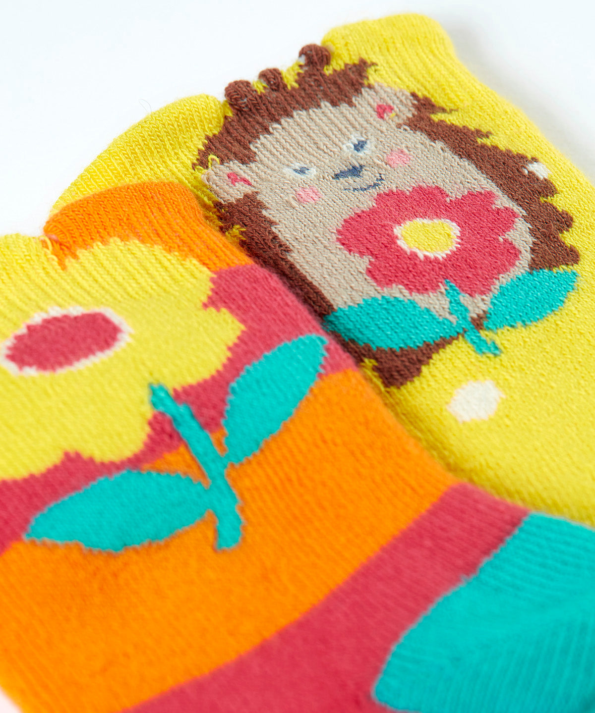 A close up of the Frugi organic cotton 2 pack socks laid flat. In bright striped hedgehog themed colours and designs