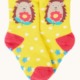 Frugi organic sock laid flat. In yellow with white spots and a hedgehog design on the ankle.