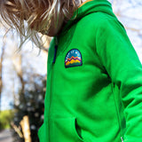 A child standing outside and wearing the green Jersey style Frugi helston reversible hoodie.