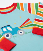 A close up of the light blue Frugi pyjama top laid flat showing the tractor design on the front and striped sleeves. 