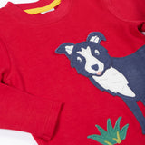 A close up of the Frugi kids adventure applique top berry red/sheepdog top showing the sheepdog applique and popper detail on red organic cotton fabric.