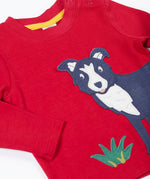 A close up of the Frugi kids adventure applique top berry red/sheepdog top showing the sheepdog applique and popper detail on red organic cotton fabric.