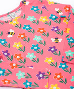 A close up of the Frugi kids bryher top in tulip fun flowers showing the playful bee and flower print detail on pink GOTs organic cotton fabric. 