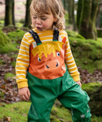 Small child wearing the Frugi water proof holly green/cow character puddle buster in the forest
