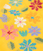 A close up of the Frugi kids carbis hoodie in bumblebee/flowers showing the the embroidery detail on yellow organic cotton fabric. 