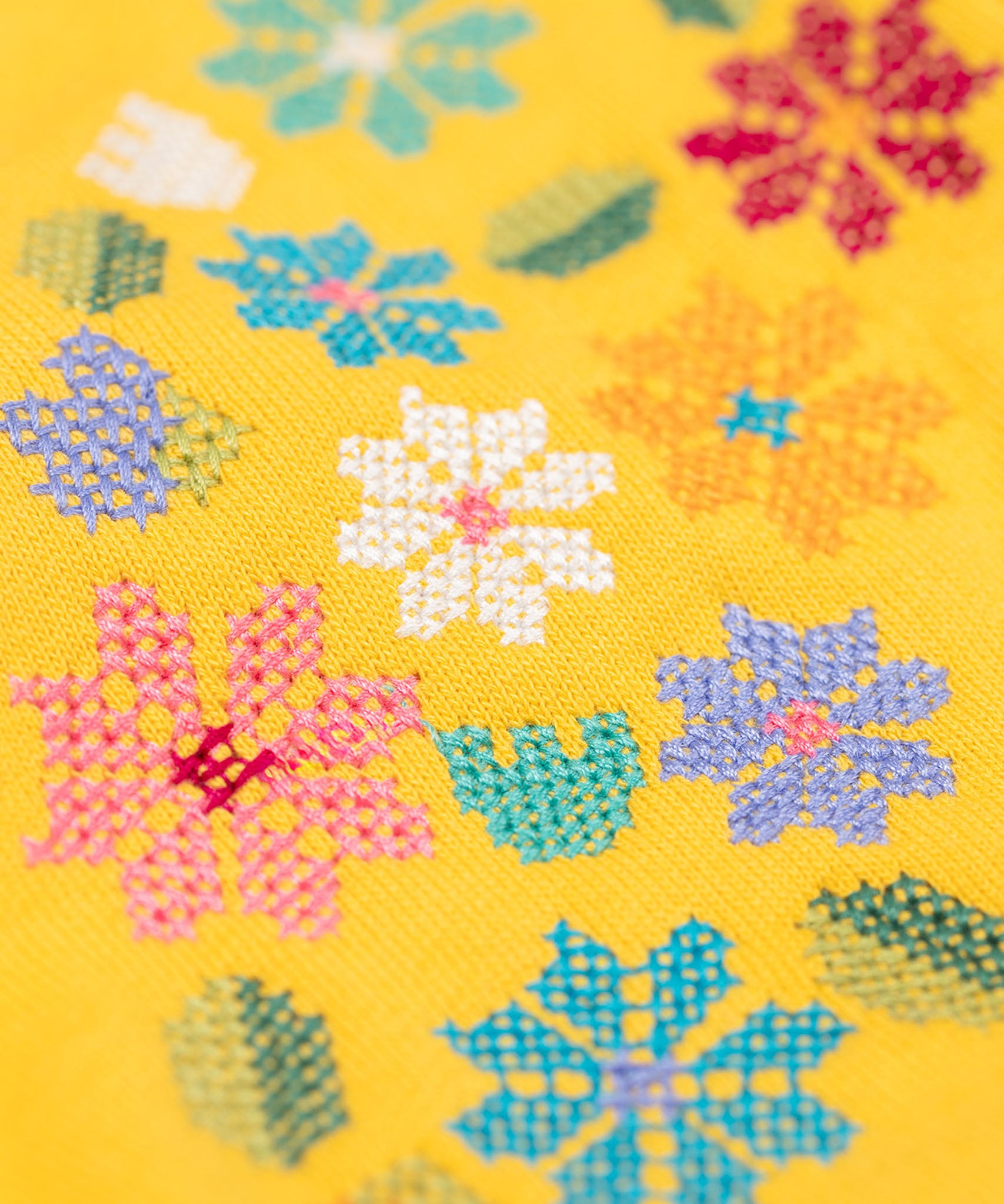 A close up of the Frugi kids carbis hoodie in bumblebee/flowers showing the the embroidery detail on yellow organic cotton fabric. 