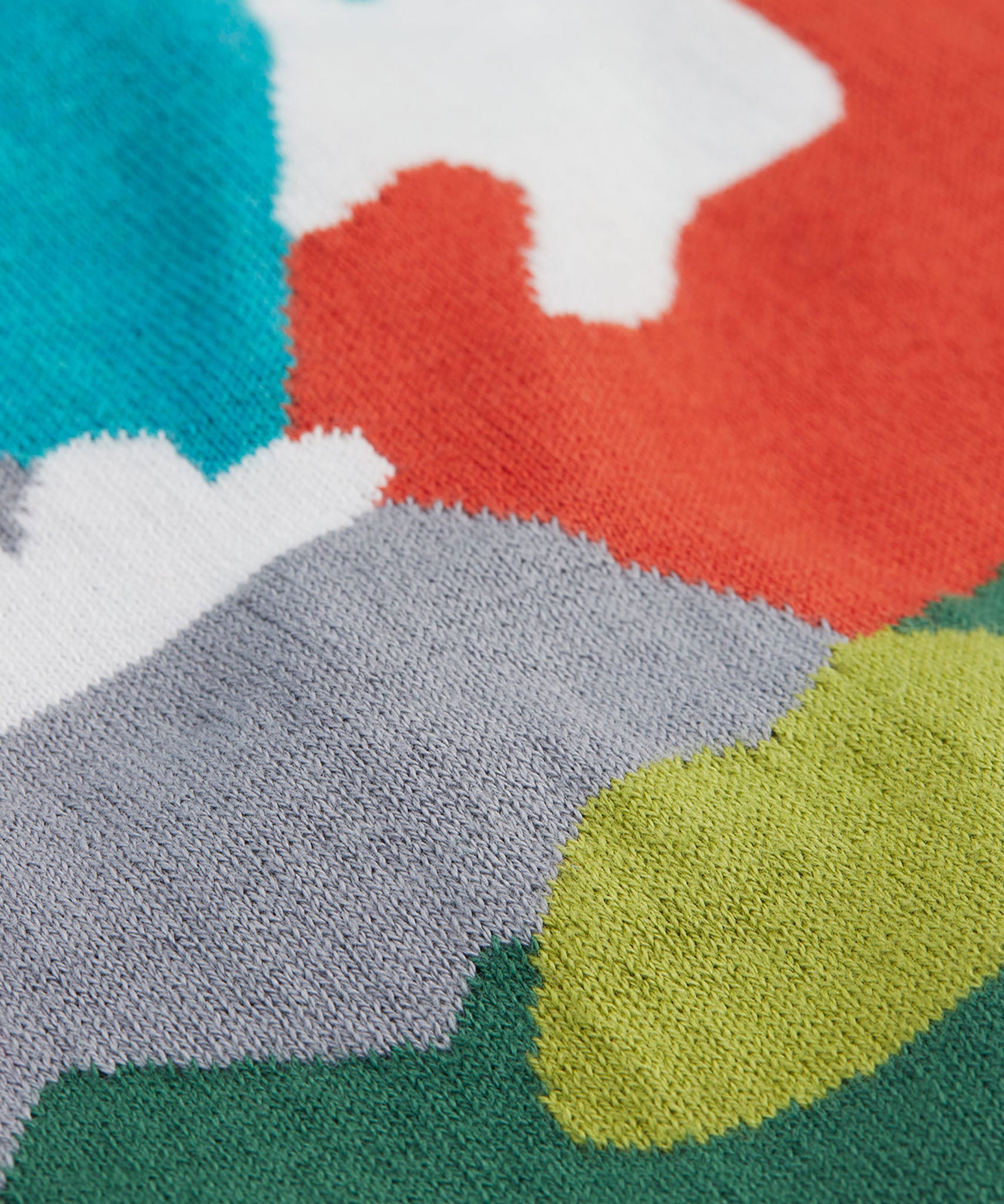 A close up of the Frugi kid reva knitted cardigan in blue/mountain scene showing the mountain scene colour detail on organic cotton fabric.