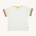 Frugi kids white short sleeve t-shirt with a rainbow trim on the sleeve on a cream background.