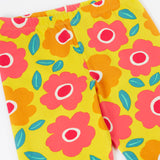 A close up of the yellow Frugi organic cotton leggings laid flat showing the repeating floral print and elasticated waist band
