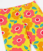 A close up of the yellow Frugi organic cotton leggings laid flat showing the repeating floral print and elasticated waist band