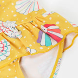 A close up of the Frugi yellow swim suit laid flat showing the repeating white shell design and frill detail on the waist.