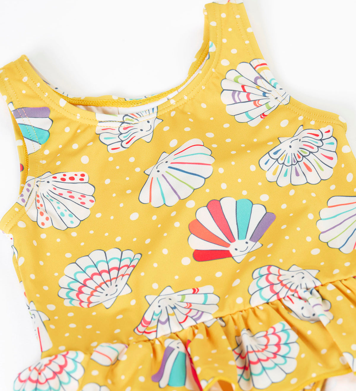 A close up of the Frugi yellow swim suit laid flat showing the repeating white shell design. 
