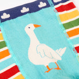 A close up of the multicoloured stripe Frugi organic cotton knitted leggings laid flat. With the white goose design on the front.