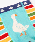 A close up of the multicoloured stripe Frugi organic cotton knitted leggings laid flat. With the white goose design on the front.
