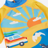 A close up of the Frugi recycled plastic sun safe swimwear all in one suit laid flat the showing sunny ocean theme design featuring a retro camper van 