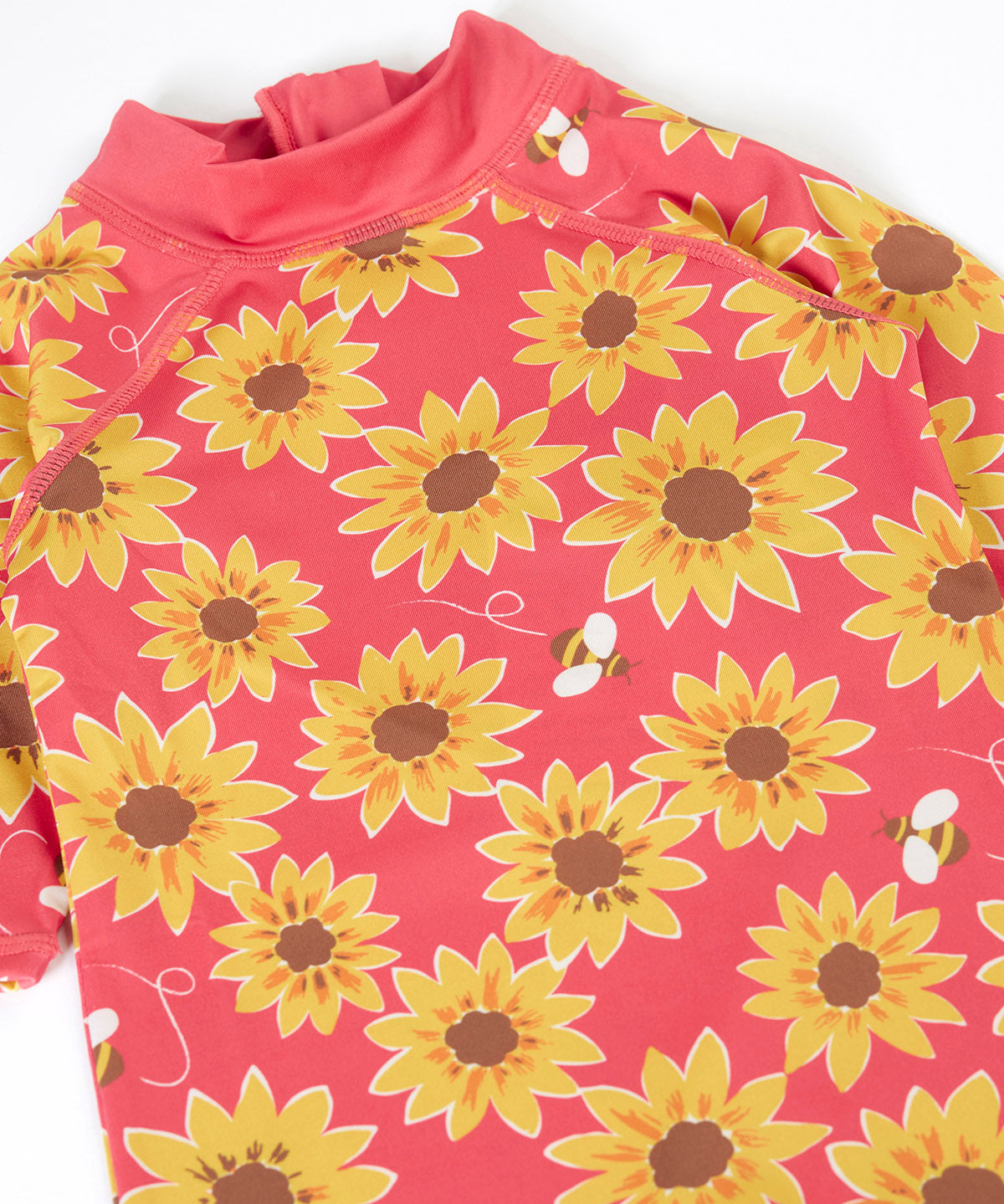 A close up of the pink Frugi all in one sun safe swimwear suit. Showing repeating yellow sunflower and flying bee print.
