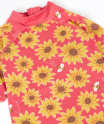 A close up of the pink Frugi all in one sun safe swimwear suit. Showing repeating yellow sunflower and flying bee print.