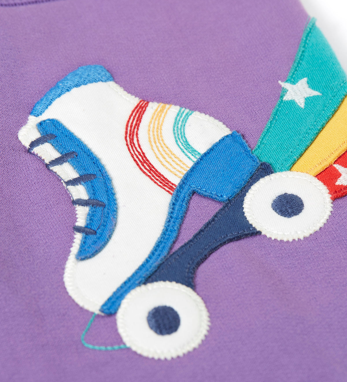 A close up of the white roller skate applique on the Frugi organic cotton purple jogger