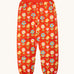 Frugi organic cotton joggers laid flat. In red with a repeating flower print and side pockets.