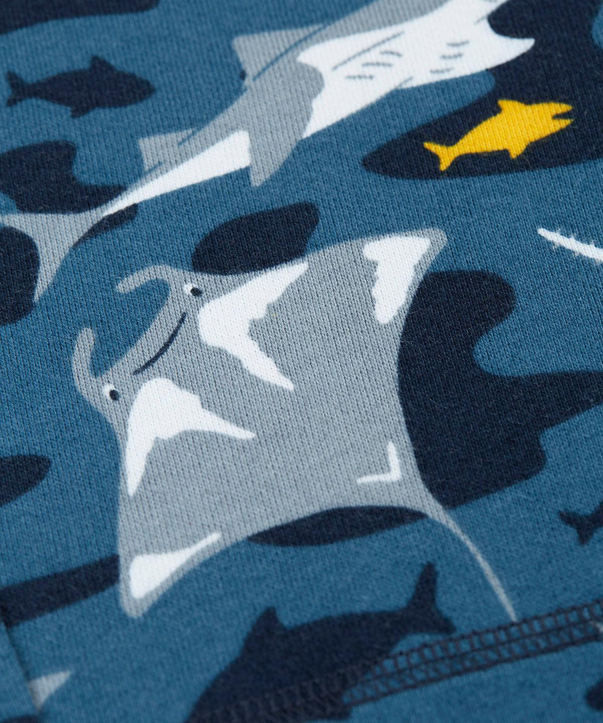 A close up of the repeating grey manta ray print on dark blue fabric 