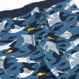A close up of the frugi joggers laid flat showing repeating grey manta ray print and the navy elasticated waist band
