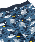 A close up of the frugi joggers laid flat showing repeating grey manta ray print and the navy elasticated waist band