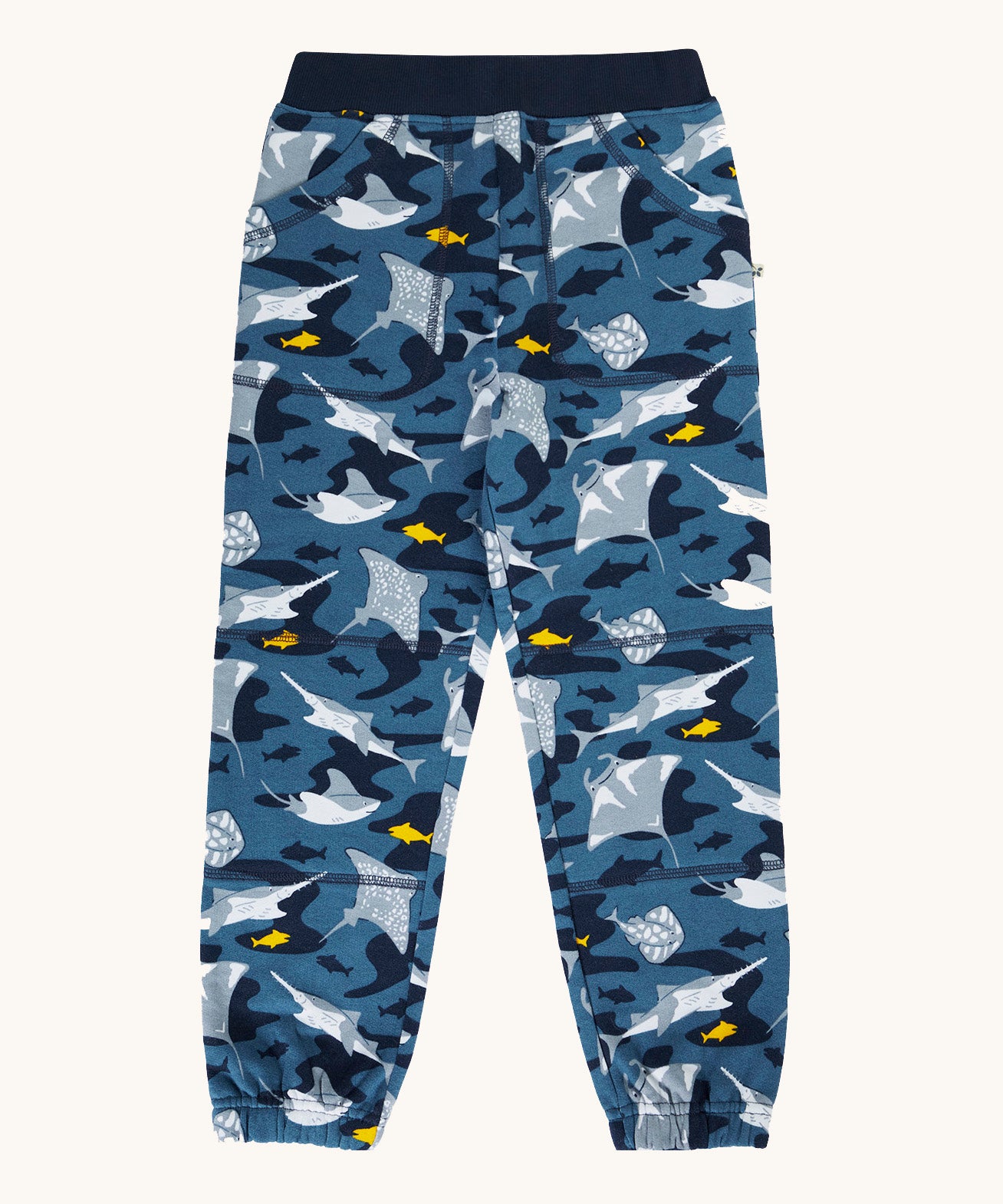 Frugi organic cotton joggers laid flat . In dark blue and navy trim with a repeating grey manta ray and shark print. 